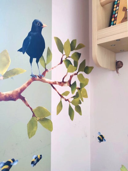 Decorative wall stickers of a blackbird on a branch with green leaves and a shelf in the background.