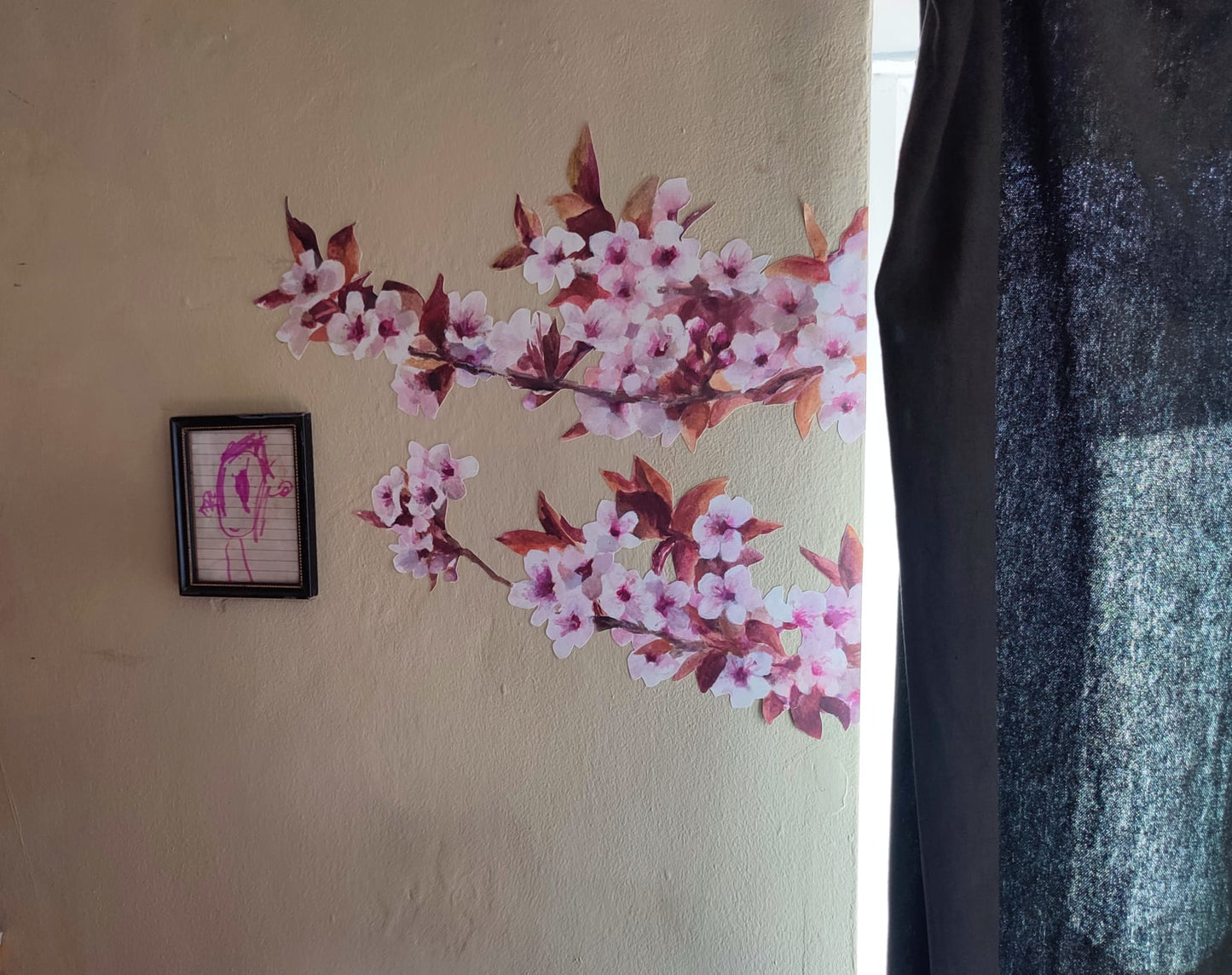 Wall with cherry blossom decals and a framed picture on a beige wall.