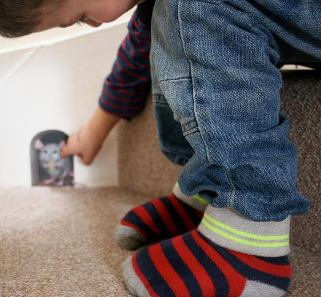 boy reaching out to touch a mouse in a mouse hole (decal) on the stairs