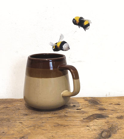 2 bumblebee decals on a white wall looking at a ceramic cup