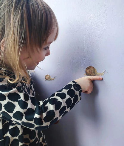 girl playing with snail decal against purple wall