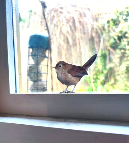 little wren decal on window frame next to bird feeder